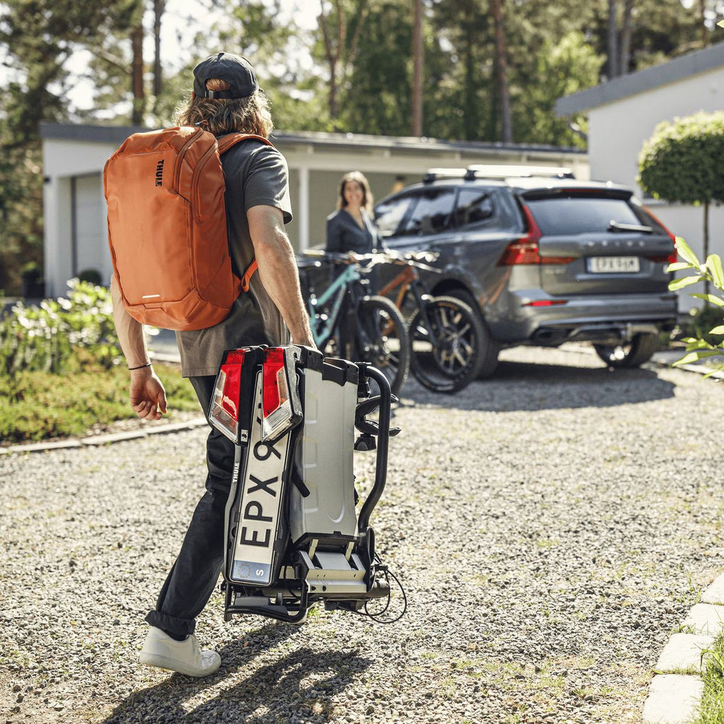 Thule EasyFold XT 2 Bike Car Bike Rack - Tow Ball mount lifestyle image, person carrying rack folded with handle